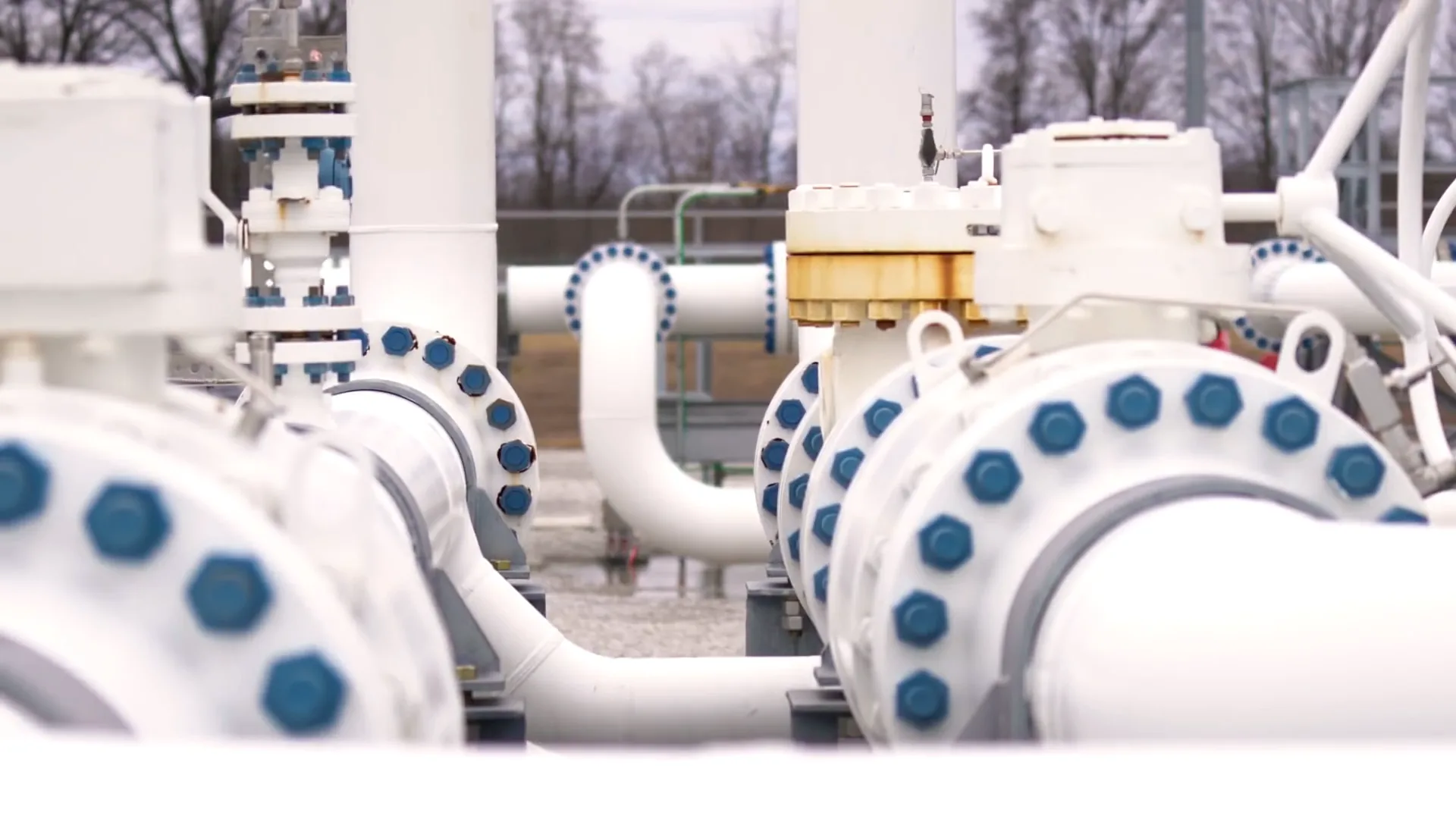 Close-up of large white flanged pipeline valves and bolted connections