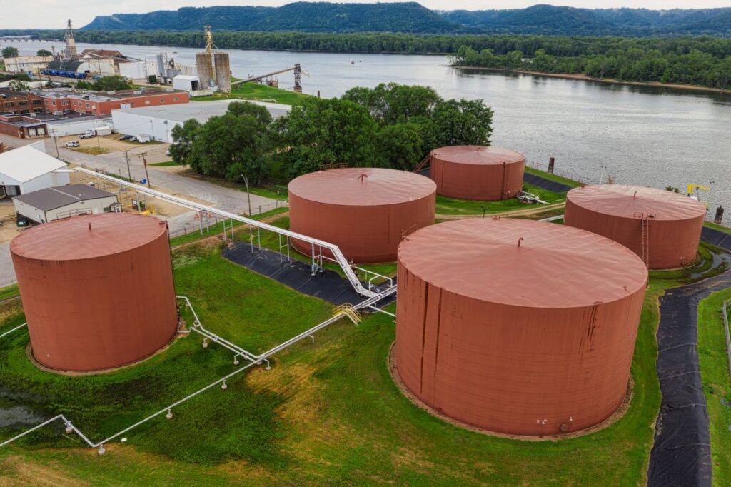 Storage tanks beside a river in a green landscape